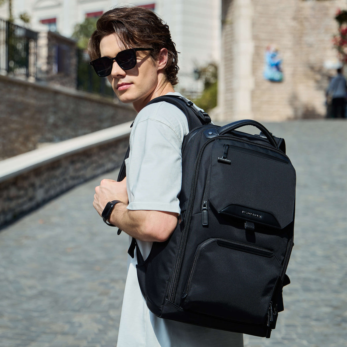 Male model wearing Nayo Smart Almighty A1 black business travel backpack city street lifestyle shot