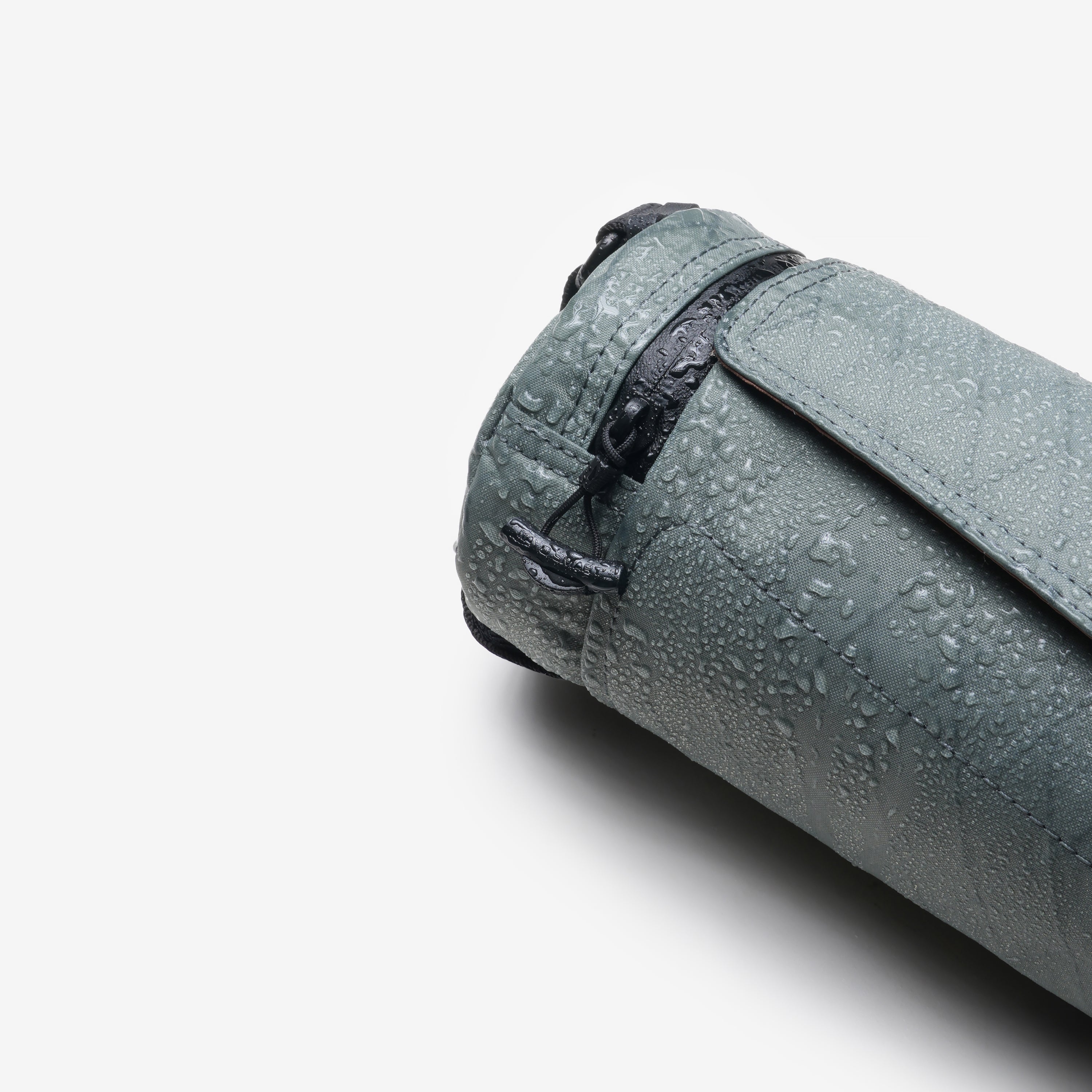 Product detail shot, Graphite Nayo Smart UL5 Cylinder Sling Bag covered with water droplets, highlighting water‑repellent X‑Pac fabric and drawstring closure