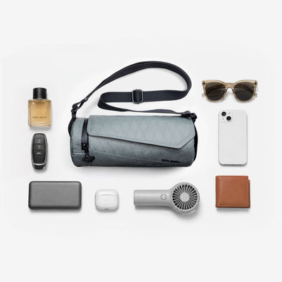 Nayo Smart Urban UL5 Cylinder Sling Bag Graphite, flat lay with everyday carry essential items