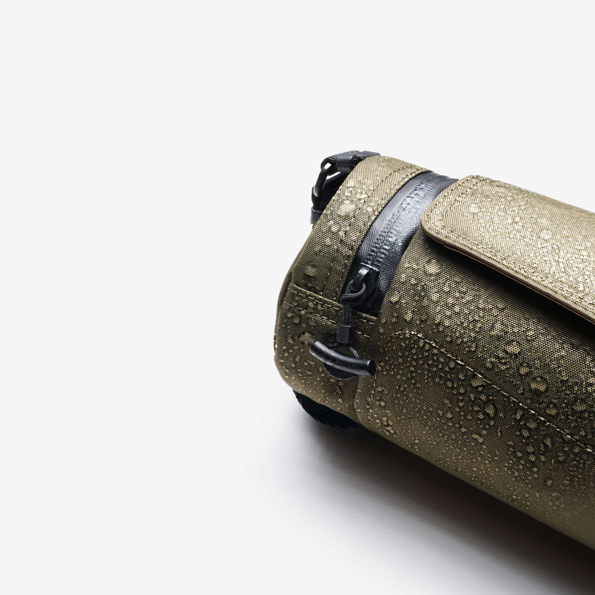 Product detail shot, Olive Nayo Smart UL5 Cylinder Sling Bag covered with water droplets, highlighting water‑repellent X‑Pac fabric and drawstring closure
