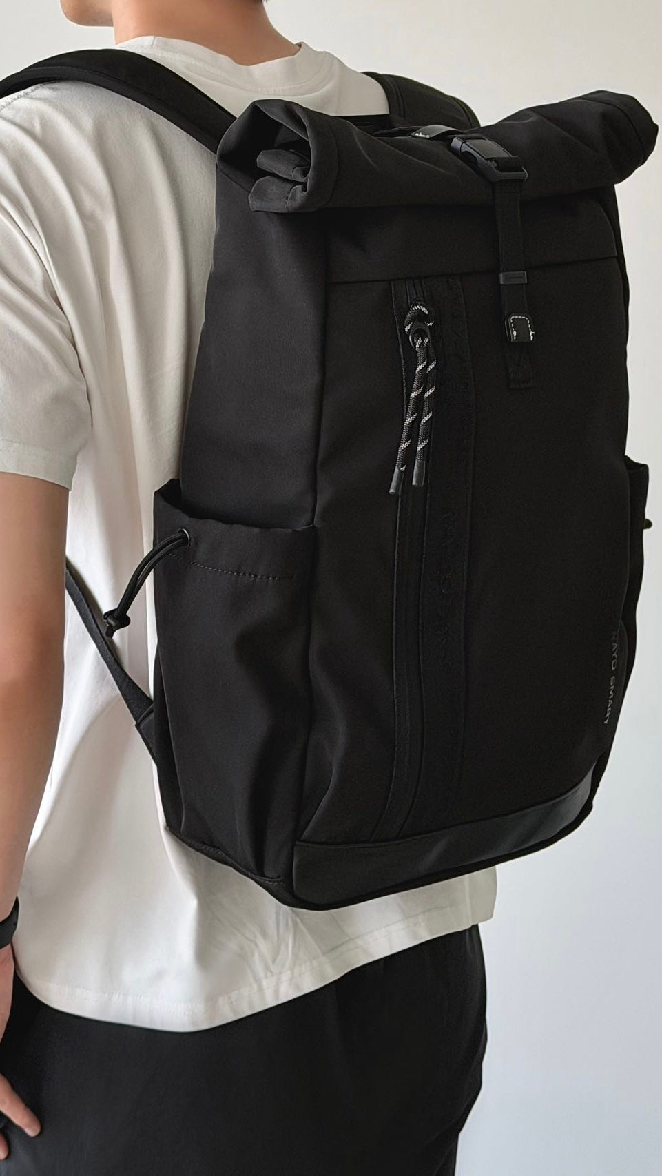 NayoSmart Urban U9 roll-top backpack black model wearing backpack back view, man carrying roll-top commuter backpack indoors