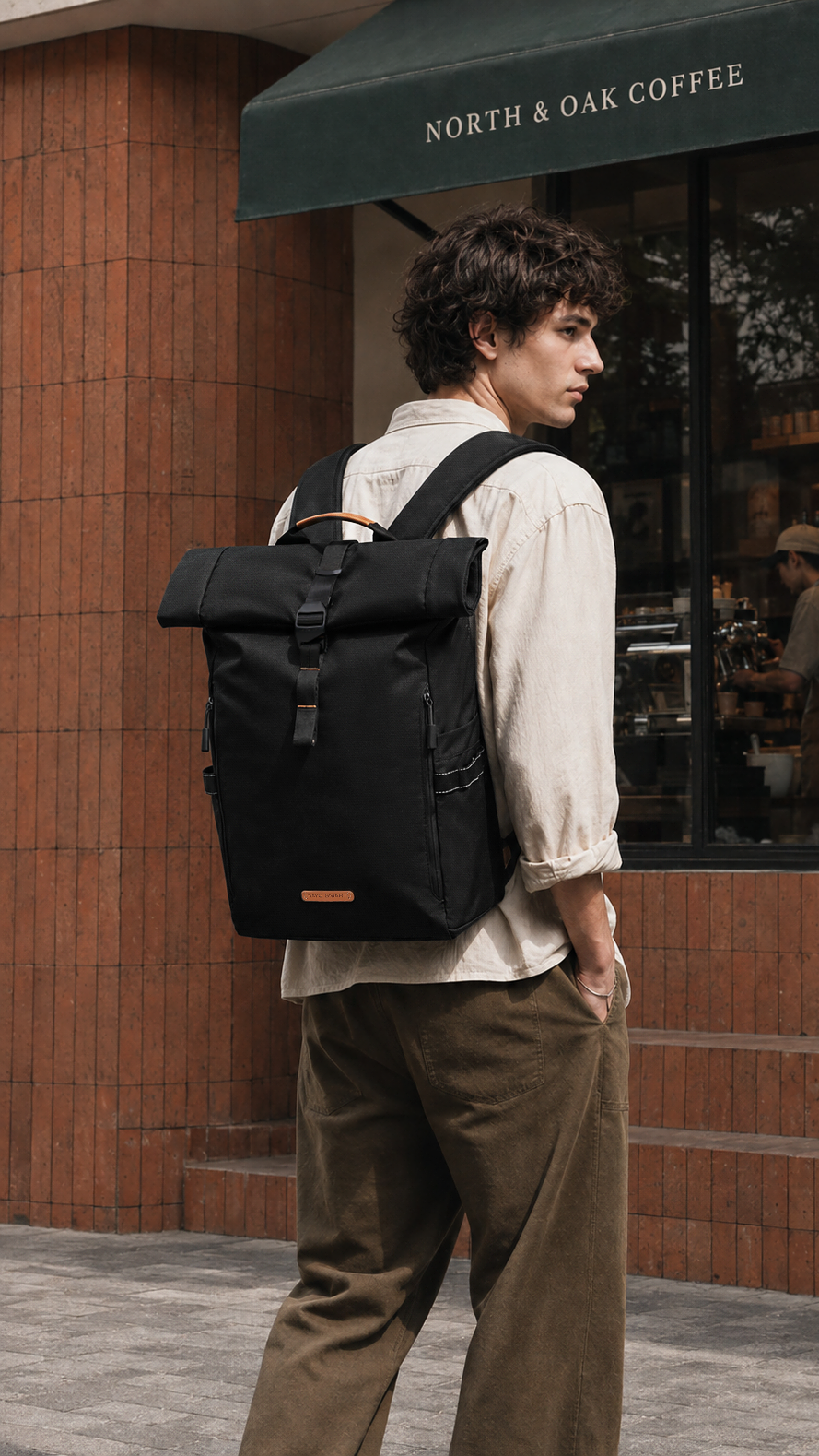 NayoSmart Urban U8 black roll‑top backpack, male model back view walking outside city cafe, urban commuter lifestyle everyday carry rucksac