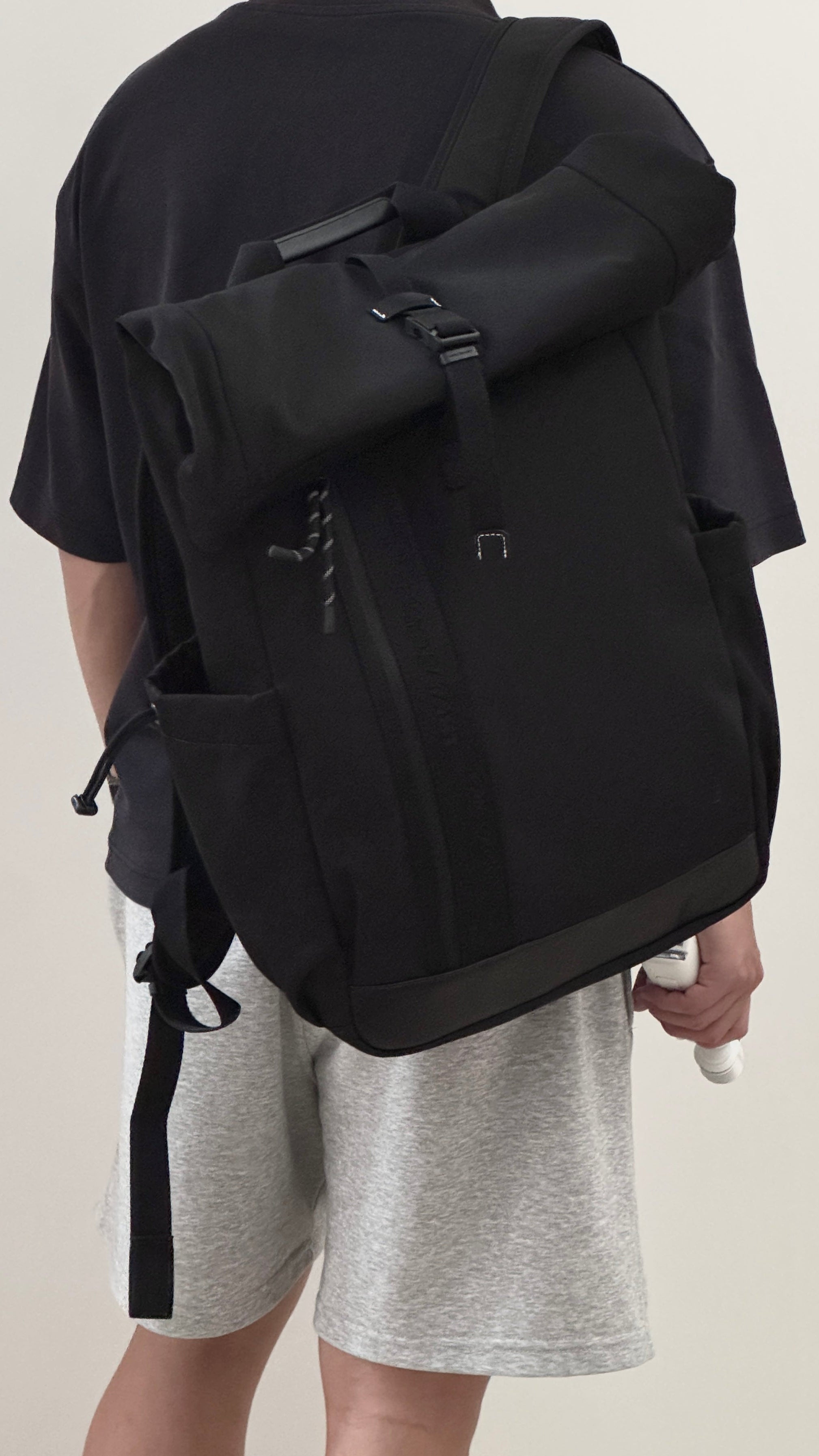 NayoSmart Urban U9 roll‑top backpack black casual daily wear back‑view shot, man in shorts carrying commuter backpack